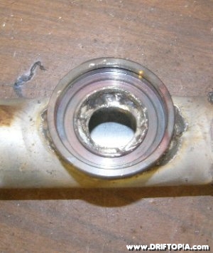 Using a drill press drill a circular hole in the pipe between the flange.