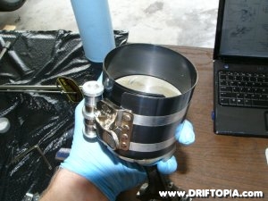The ring compressor around the newly installed piston rings.