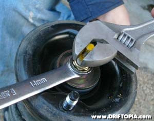 Remove the mount by holding the strut rod with an adjustable wrench and loosening the bolt.