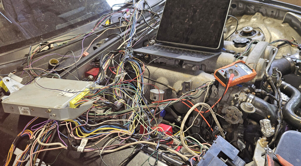 NA 1.6l Miata MX-5 with the wiring harness and ECU laying across the engine bay for troubleshooting.